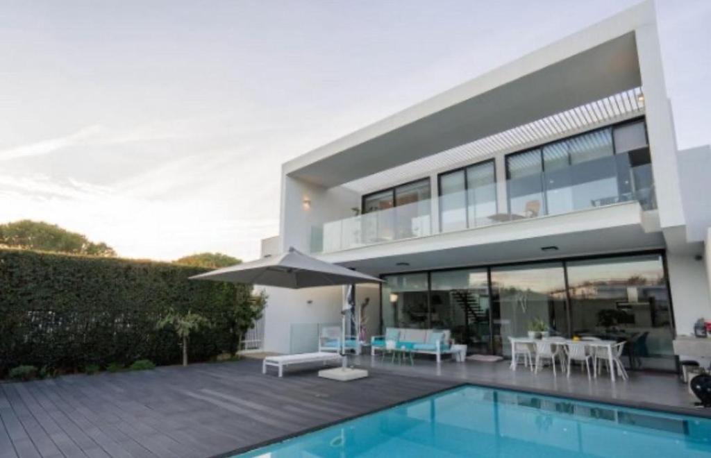 a house with a swimming pool and an umbrella at Luxurious Villa Vilamoura in Vilamoura