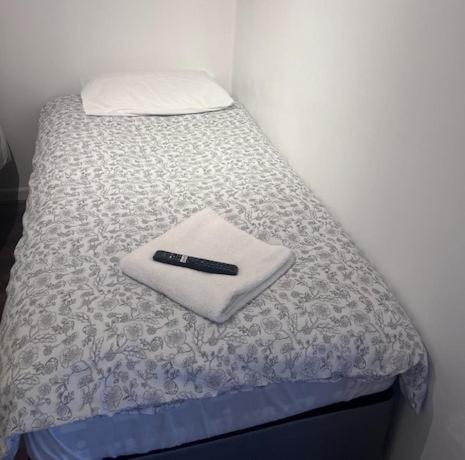 a bed with a remote control sitting on top of it at Solihull Guest House 1 in Olton