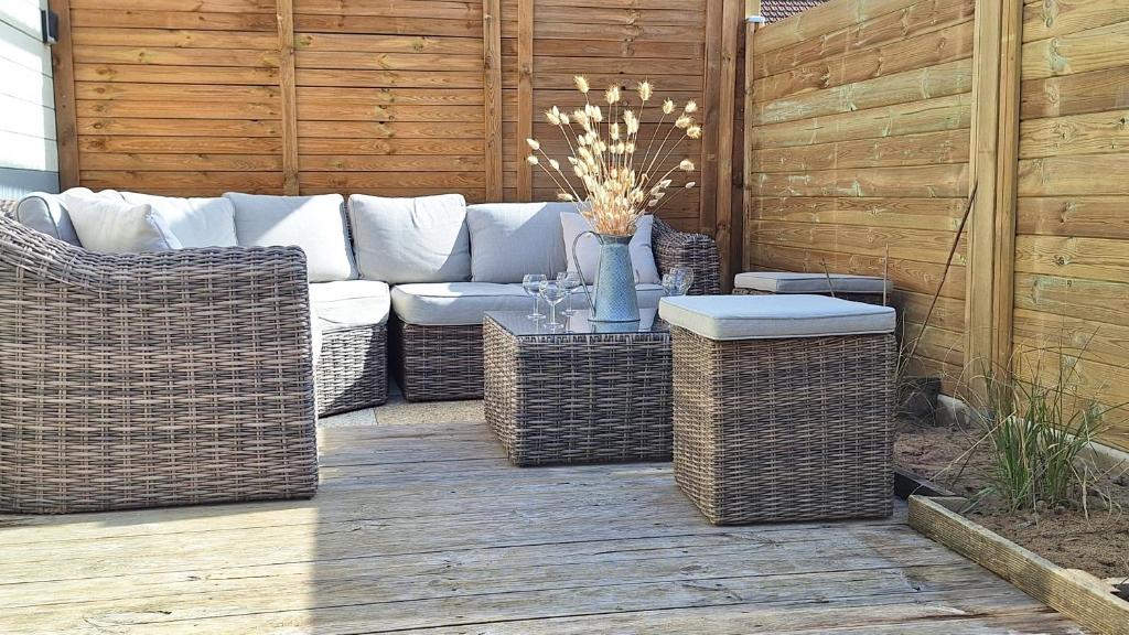 un patio avec un canapé, des chaises en osier et une table dans l'établissement A seulement 150m plage et commerces maison 90m2 4 pièces avec parking privé et 2 terrasses sud, à Saint-Jean-de-Monts