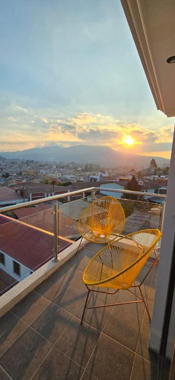 2 sillas en un balcón con la puesta de sol en el fondo en Apartamento 1 Premiere de Occidente en Quetzaltenango