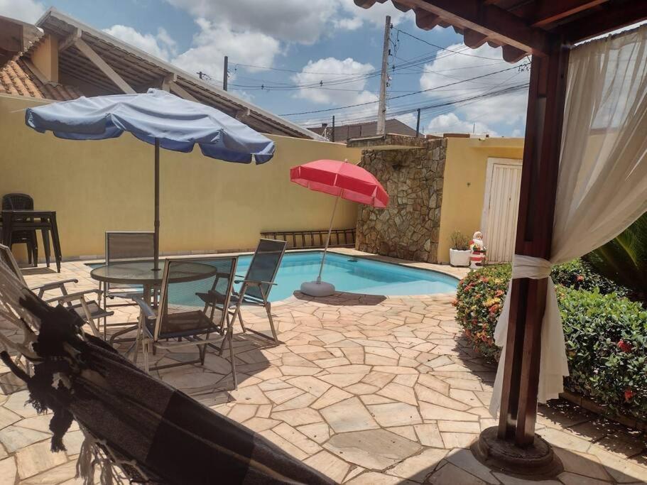 un patio con mesa, sombrilla y piscina en Casa em Ribeirão Preto Agrishow e Eventos, en Ribeirão Preto