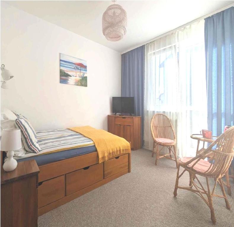 1 dormitorio con 1 cama, TV y silla en FLORIAN - tuż przy plaży, en Mielno