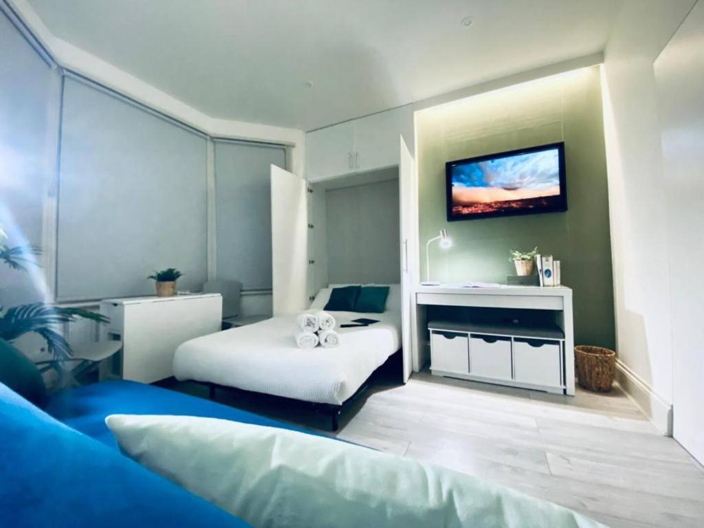 a bedroom with a bed and a tv on the wall at Apt 06 Stylish Studio steps from Beach, Cafe's & Bar's in Brighton & Hove