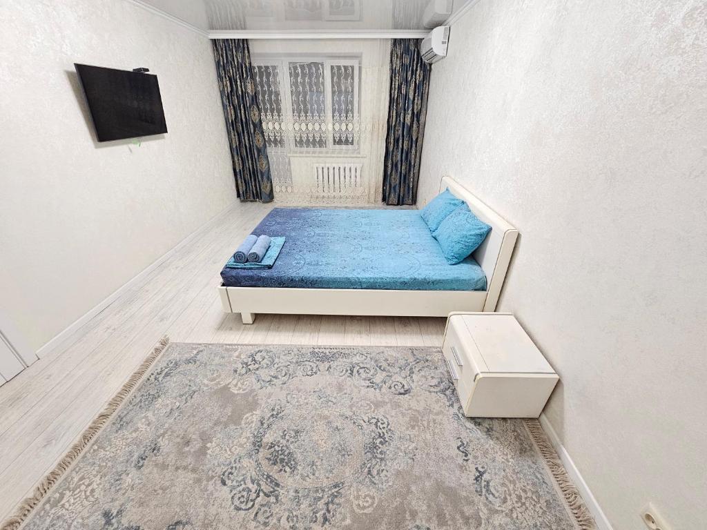 um pequeno quarto com um sofá azul e uma janela em Sapar APARTMENTS 24 em Aqtöbe