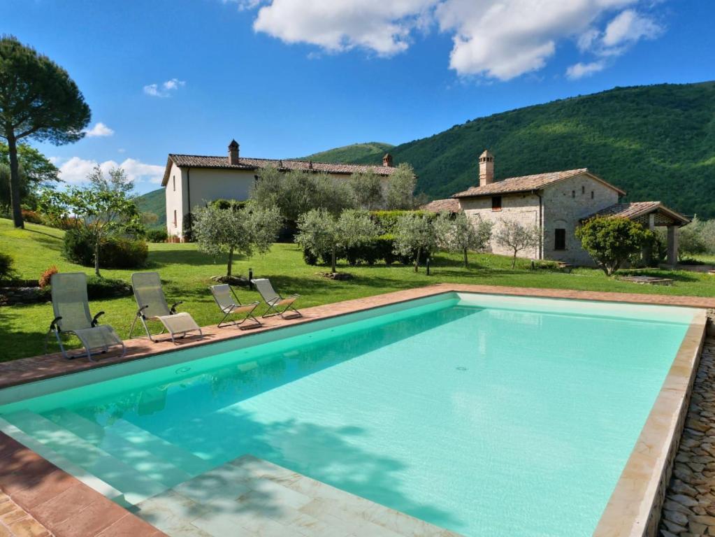 uma piscina com cadeiras e uma casa ao fundo em M&M Holiday House Umbrian Modern House with Swimming Pool em Antognola