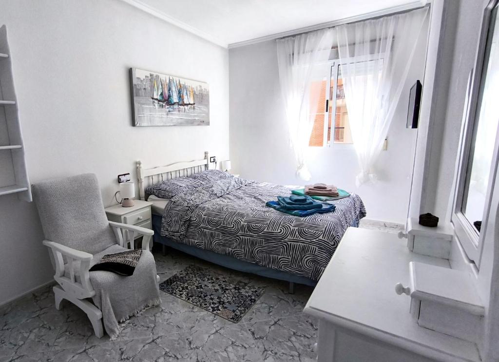 a bedroom with a bed and a chair and a window at Alba Apartman Torrevieja in Torrevieja