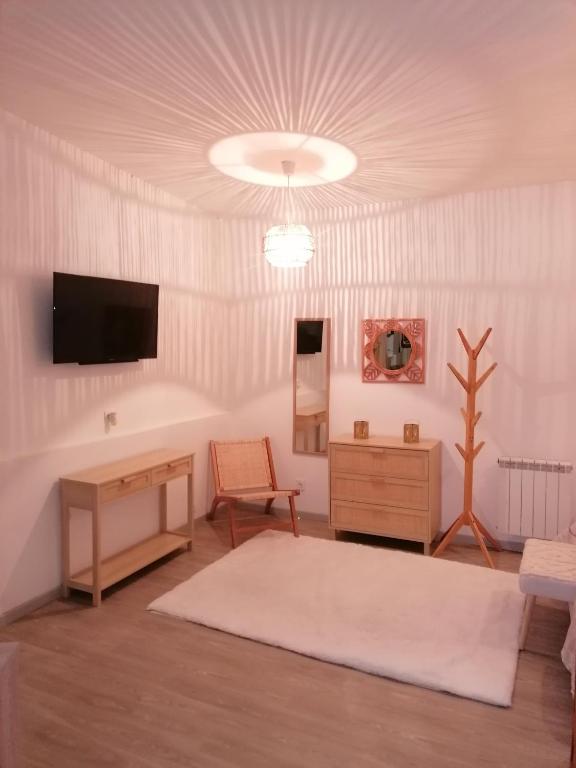 ein Wohnzimmer mit einem Tisch und einem TV an der Wand in der Unterkunft L'orientale in Rouvroy