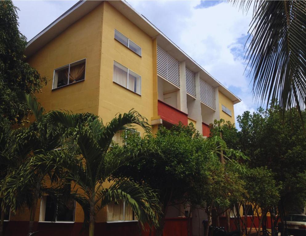 um edifício amarelo com árvores em frente em Apartamentos Sol de Coveñas em Coveñas