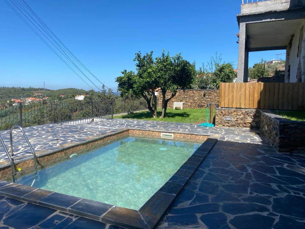 a small swimming pool in a yard with a house at Casa da Meia Encosta in Arganil