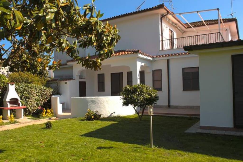 a large white house with a green yard at Confortevole Villino a San Felice Circeo in San Felice Circeo