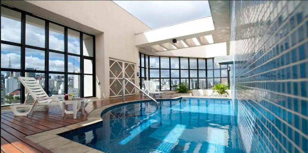 LONG STAY APART HOTEL NINETY JARDINS - Alameda CAMPINAS , CUSTO BENEFICIO!! في ساو باولو: مسبح كبير في غرفة كبيرة مع نوافذ