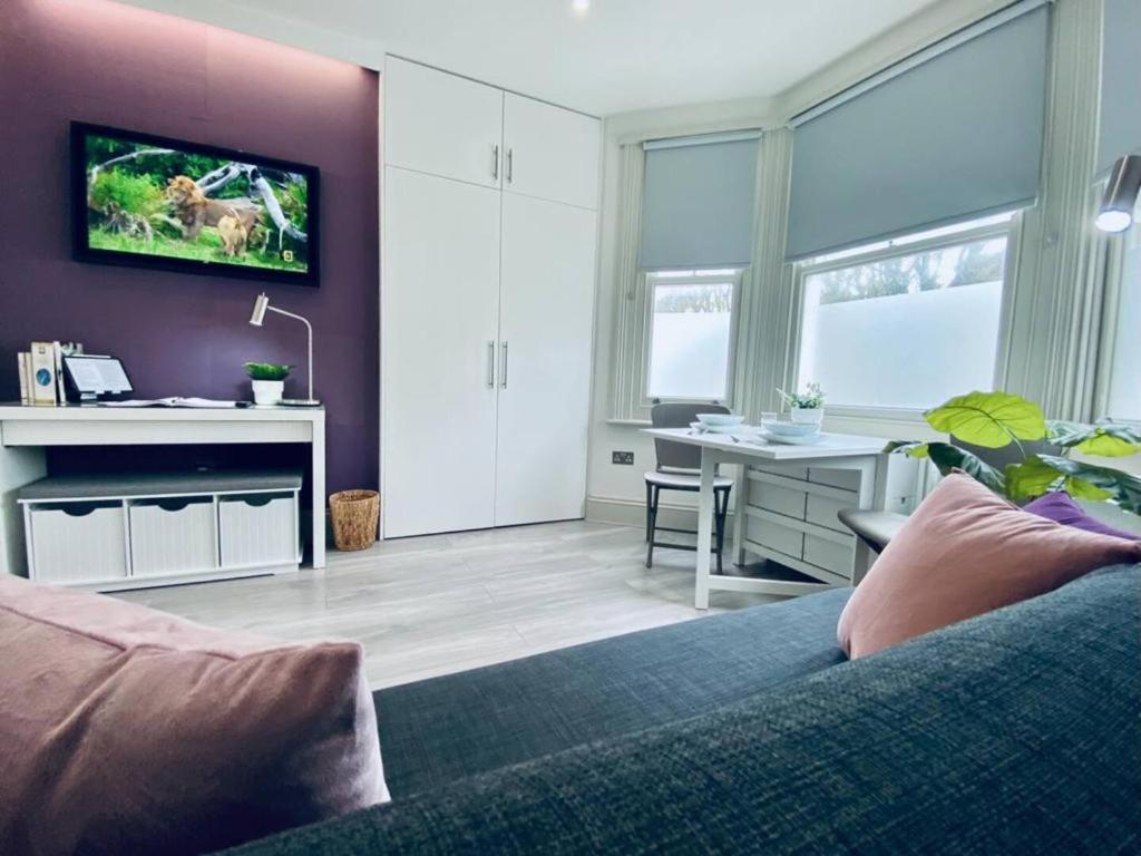 a living room with a couch and a table with a desk at Apt 07 Beachside Beauty Central Studio Steps from Cafes in Brighton & Hove