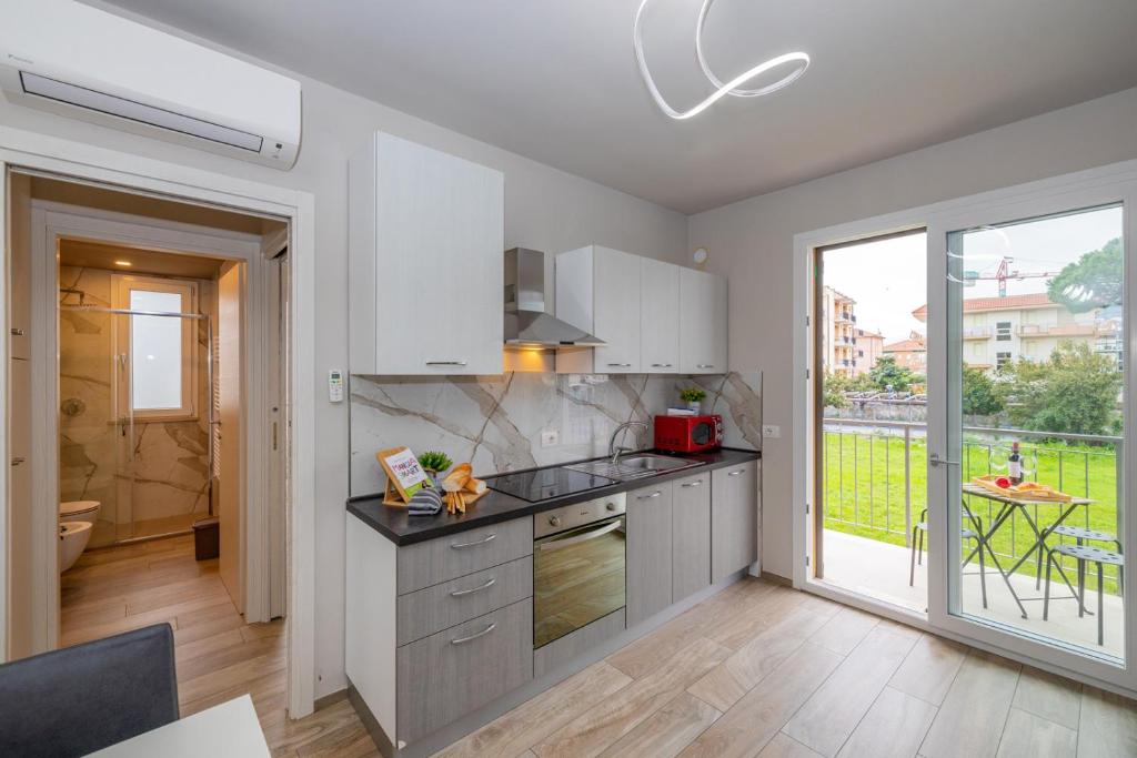een keuken met witte kasten en een groot raam bij La Casa Nuova - Pietra Ligure in Pietra Ligure