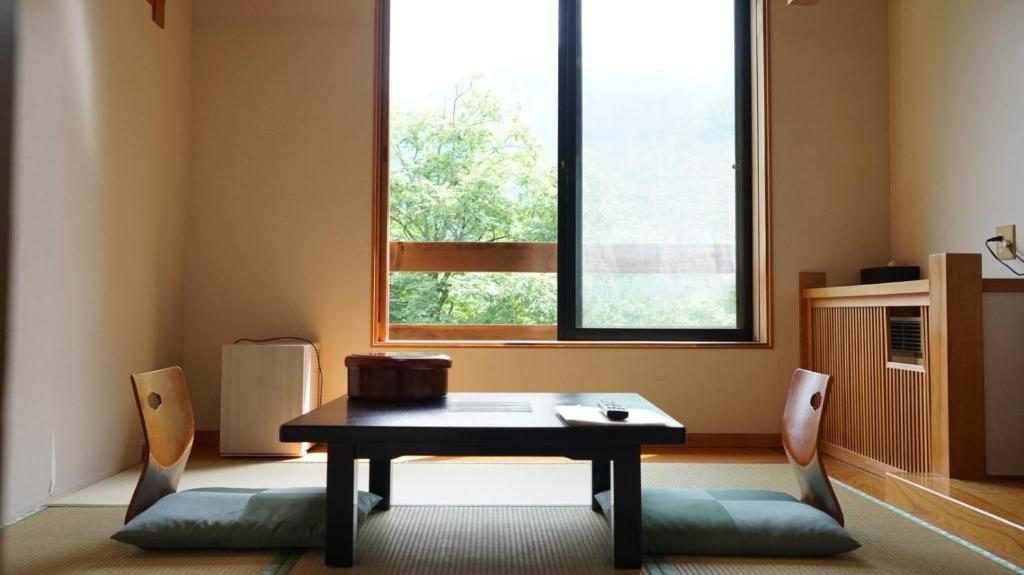 tavolo e sedie in una stanza con finestra di Nakanoyu Onsen Ryokan - Vacation STAY 18829v a Matsumoto