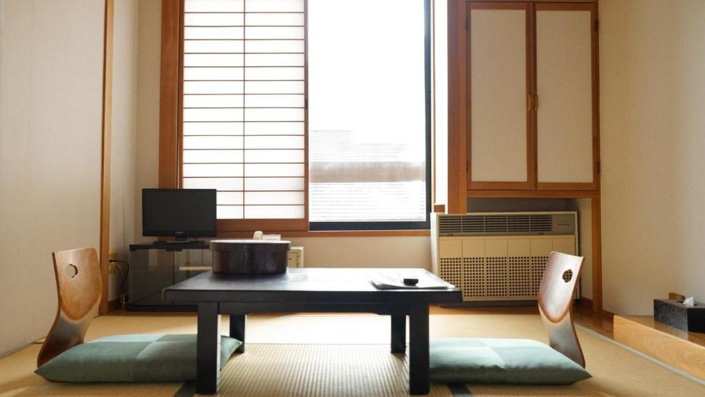 ein Wohnzimmer mit einem Tisch, Stühlen und einem Fenster in der Unterkunft Nakanoyu Onsen Ryokan - Vacation STAY 18804v in Matsumoto