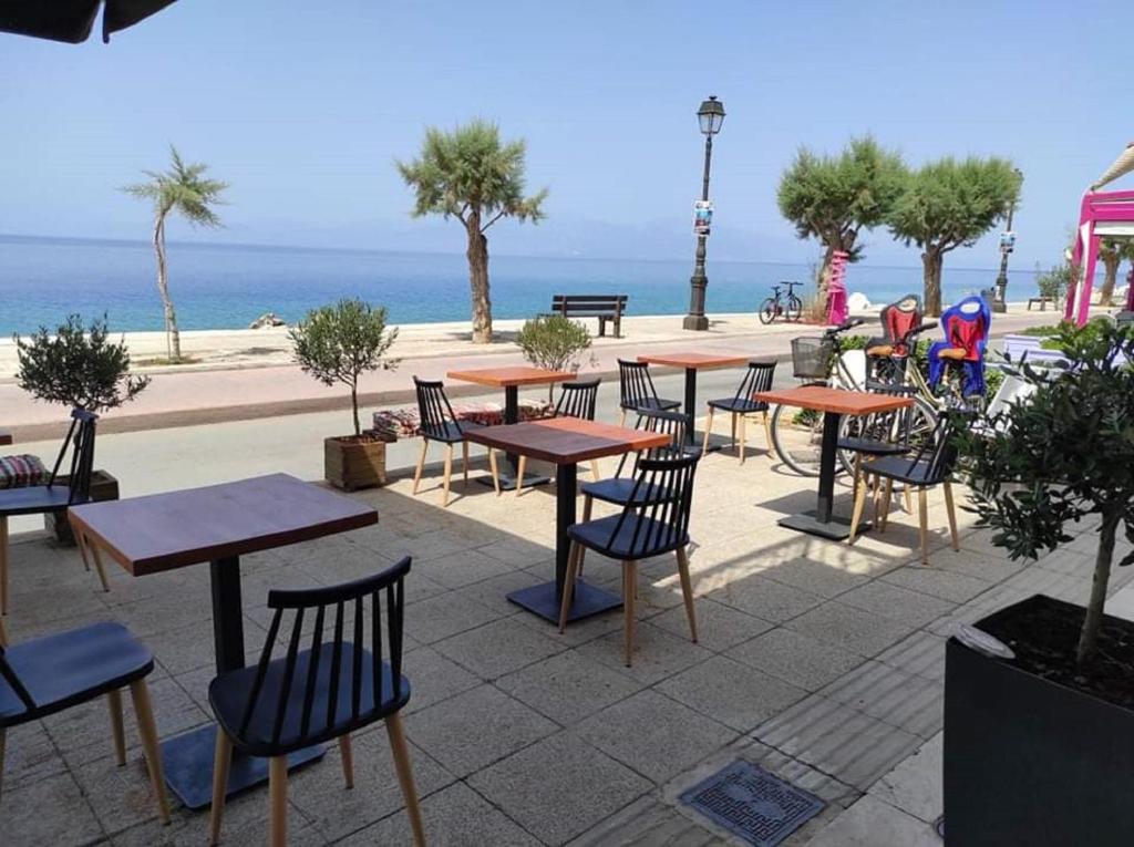西洛卡特倫的住宿－Hotel Kyani Akti，一组桌子和椅子,背景是海洋