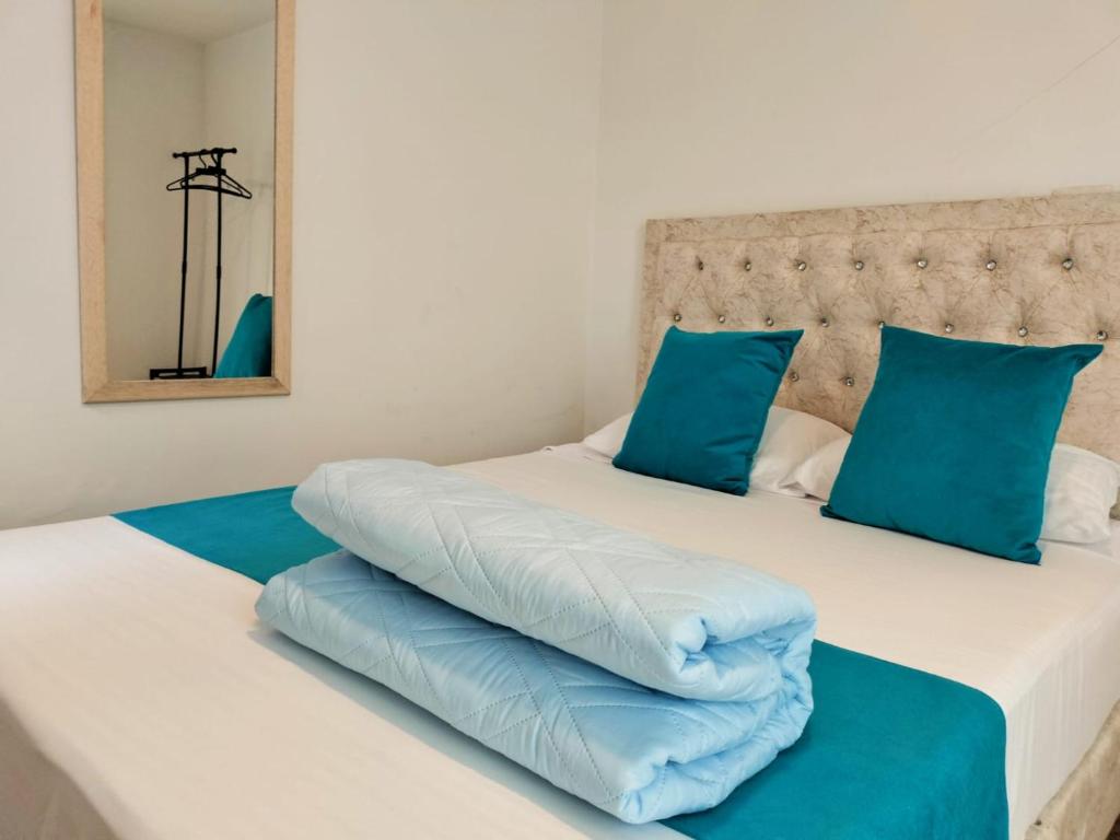2 camas con almohadas azules juntas en Hotel Batan 127, en Bogotá