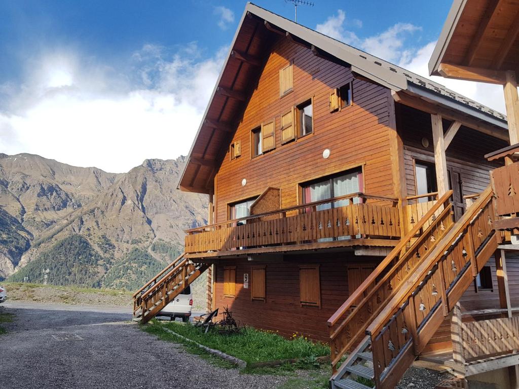 a large wooden house with a balcony and mountains at Duplex dans chalet au coeur de la station in Réallon