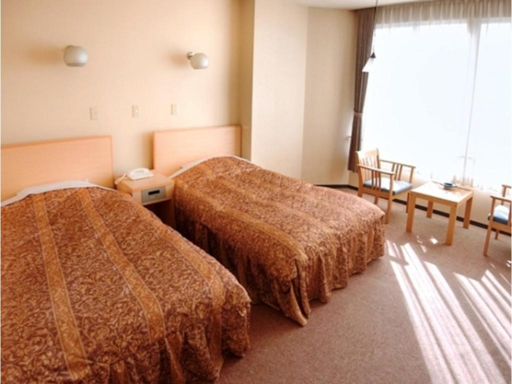 鳥取市にあるTottori Onsen Shiitake Kaikan taisuikaku - Vacation STAY 21957vのベッド2台と窓が備わるホテルルームです。