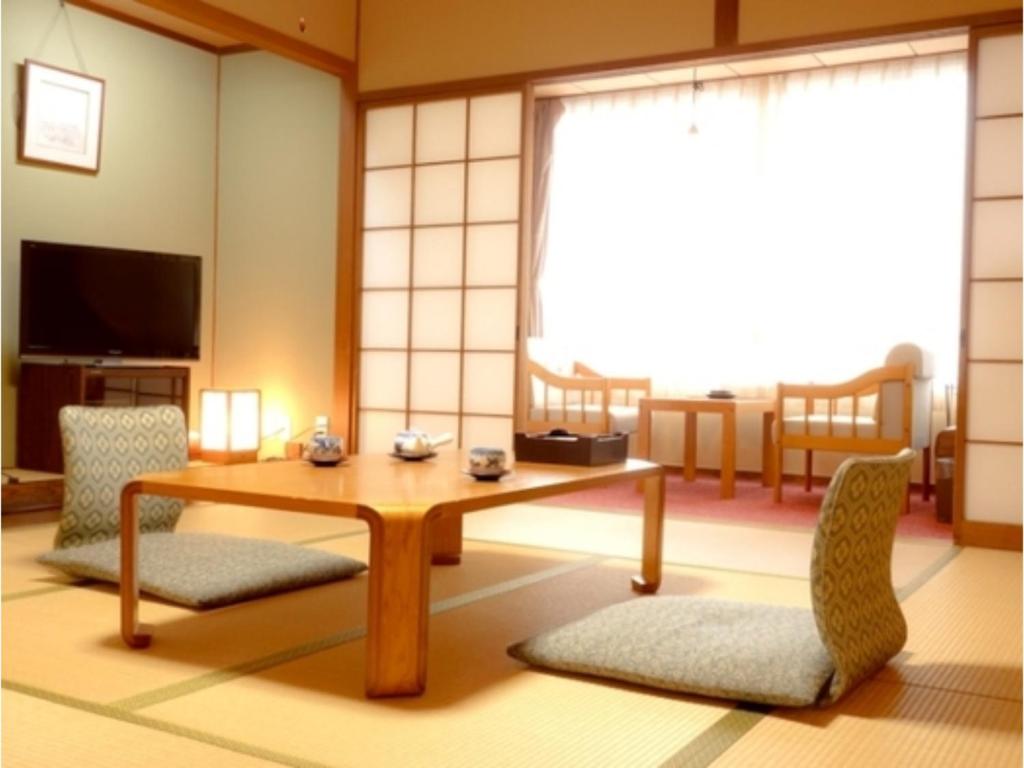 un soggiorno con tavolo e 2 sedie di Tottori Onsen Shiitake Kaikan taisuikaku - Vacation STAY 21943v a Tottori