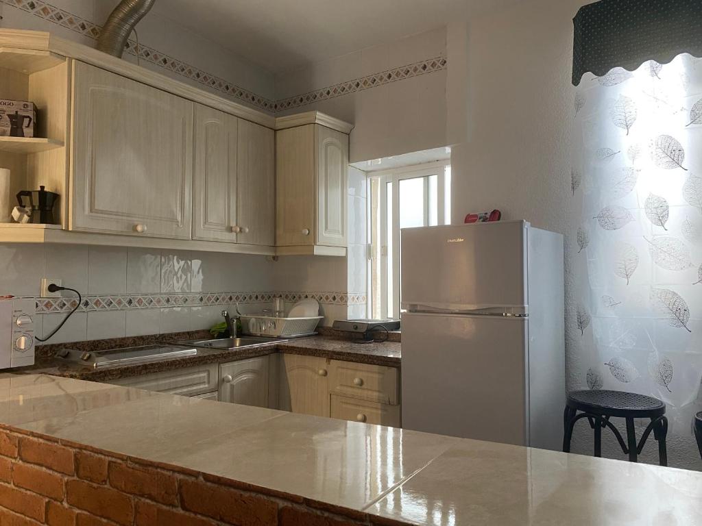 La cuisine est équipée de placards blancs et d'un réfrigérateur blanc. dans l'établissement apartamento turístico CUATRO CAMINOS, à San Vicente de Alcántara