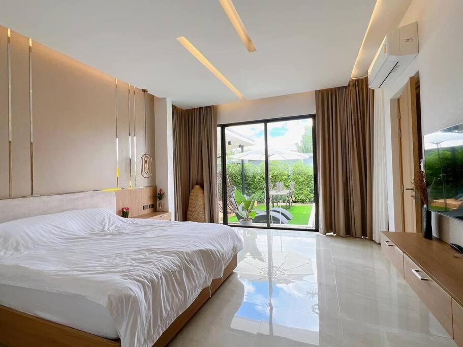 a bedroom with a large bed and a large window at Anya Pool Villa Pattaya in Ban Huai Yai