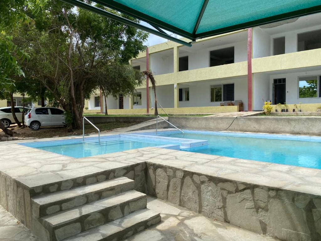 a swimming pool in front of a building at Lagos Diani in Diani Beach