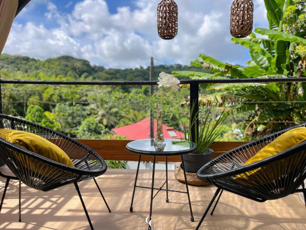d'une terrasse avec 2 chaises et une table avec un vase. dans l'établissement Cocon des jardins - Bungalow & SPA, à Gros-Morne