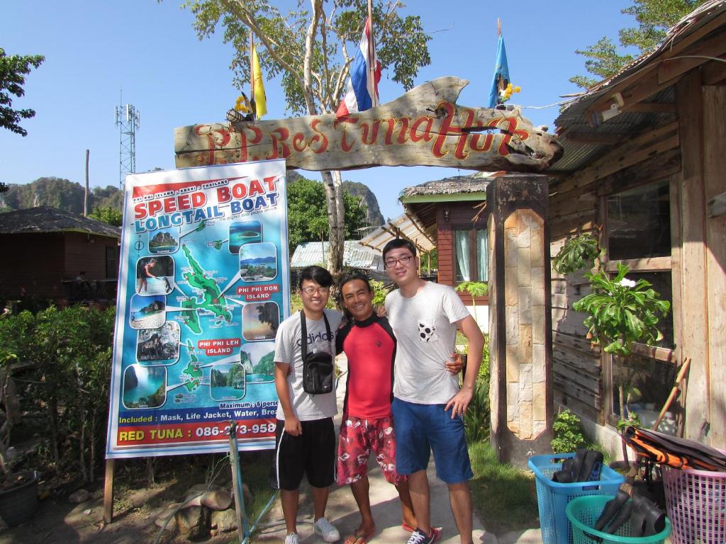 a group of three men standing in front of a sign at PP Red Tuna Hut in Phi Phi Don