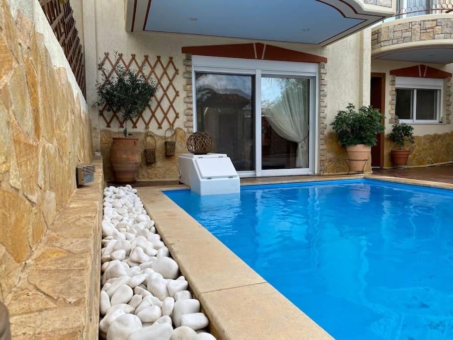 a swimming pool with rocks next to a house at Pool Garden House near the Sea in Vari