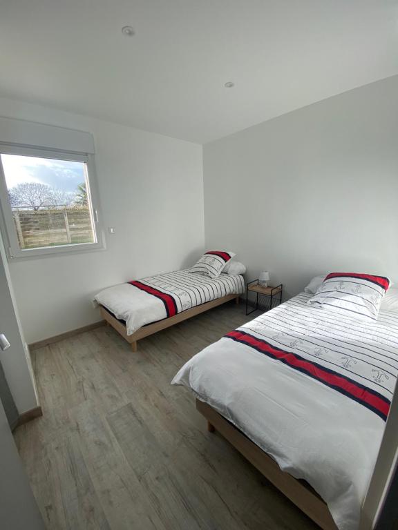 two beds in a white room with a window at Les gîtes Pléhédelais TER in Pléhédel