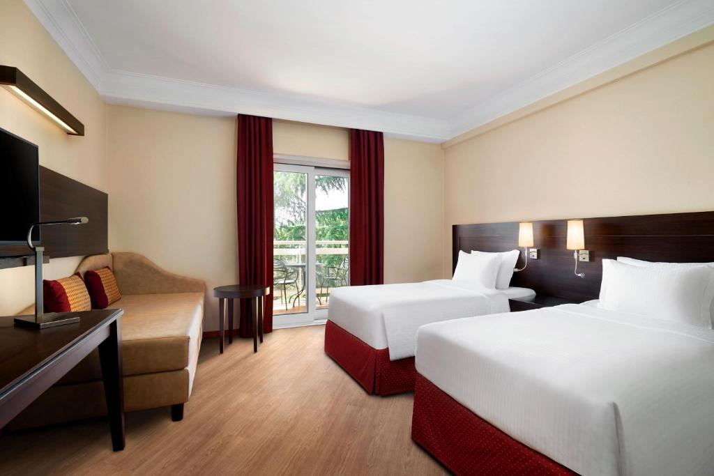 pokój hotelowy z 2 łóżkami i kanapą w obiekcie Courtyard by Marriott Rome Central Park w Rzymie