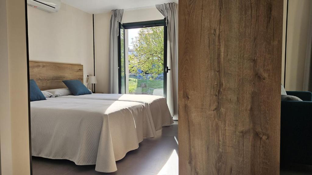 a bedroom with a bed and a large window at Apartamentos O Caneiro in Portomarin