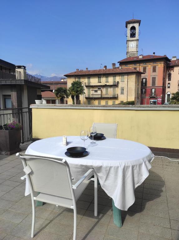 une table et des chaises blanches sur un balcon avec une tour d'horloge dans l'établissement Appartamento Campanile, à Luino