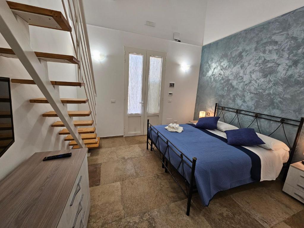 een slaapkamer met een bed met blauwe lakens en een trap bij B&b Ètoile Salento in Arnesano