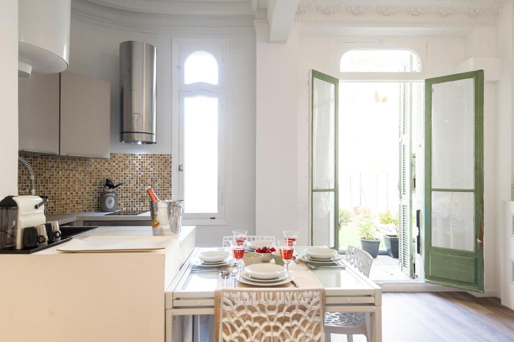 a kitchen with white cabinets and a table with chairs at Appartements Massena in Nice