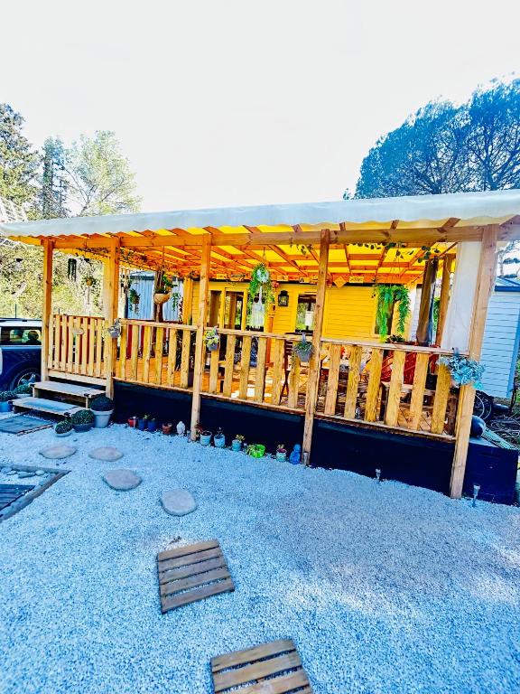 une maison jaune avec une terrasse couverte et une terrasse dans l'établissement Mobilhome 45m2, à Roquebrune-sur Argens