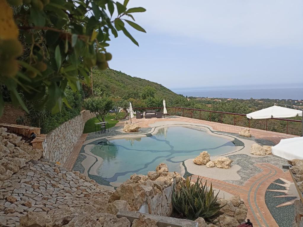 una piscina con un muro di pietra intorno di Il Corbezzolo Tropea Residence a Tropea