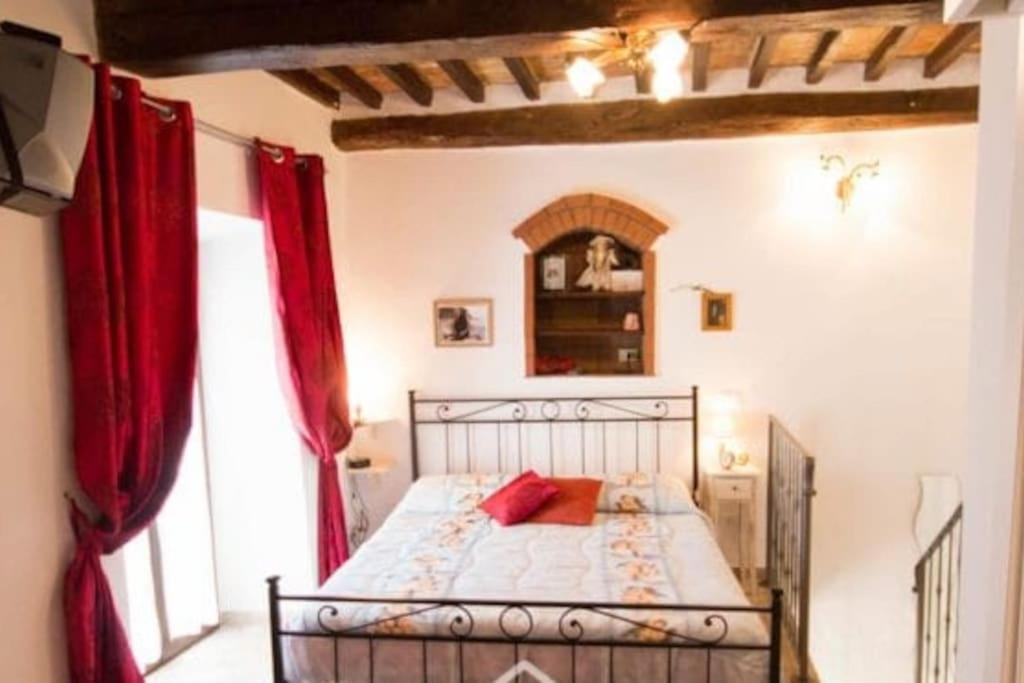 een slaapkamer met een bed met rode gordijnen bij Casa Il girasole in Boccheggiano
