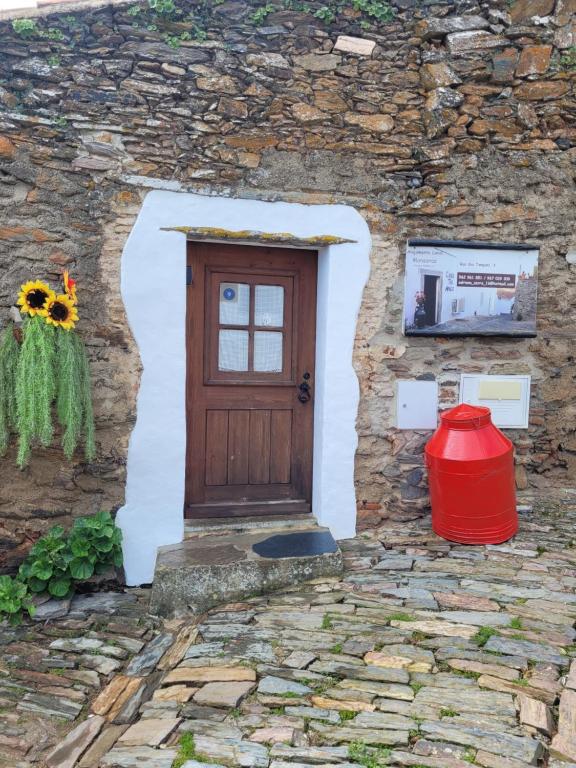 a door in a stone building with a red bucket at Estúdio Tia Anica in Reguengos de Monsaraz