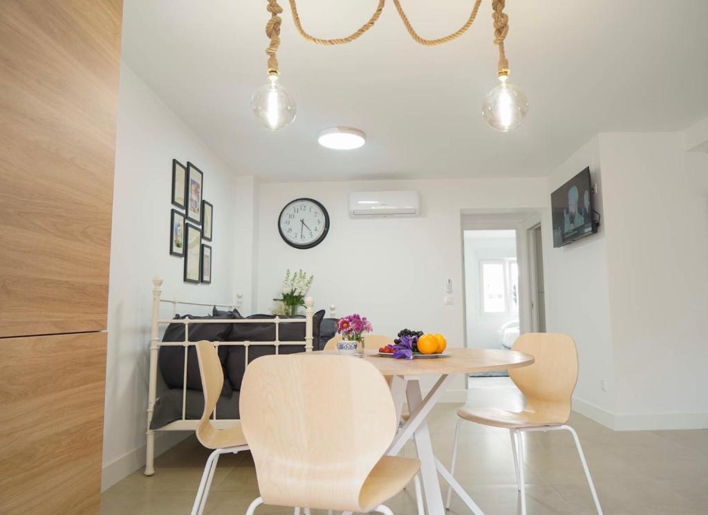 a dining room with a table and chairs and a clock at Apartamento Ágüelos in Madrid