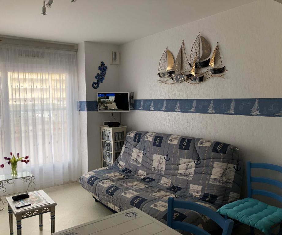 - un salon avec un lit et un bateau sur le mur dans l'établissement Le Triskel - Studio à 50 mètres de la plage, à Fort-Mahon-Plage