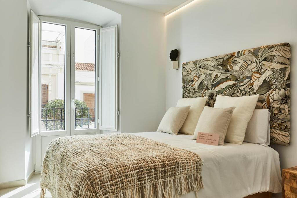een witte slaapkamer met een bed en een groot raam bij LUPERCAS in Merida