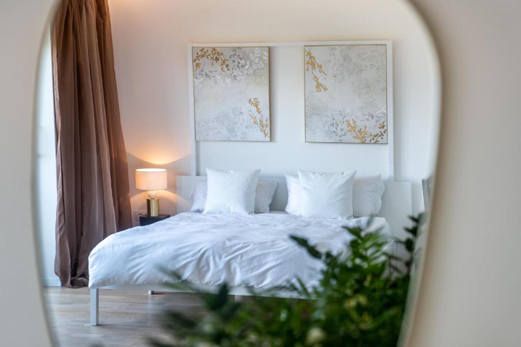 um quarto com uma cama branca e um espelho em Villa Maria Boutique Apartment St Pauls em Appiano sulla Strada del Vino