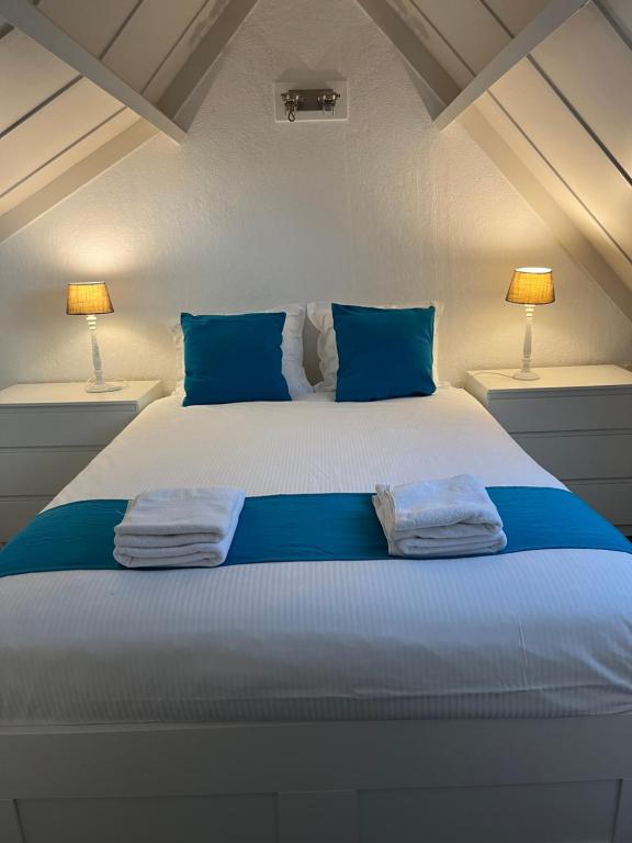 a white bed with blue pillows and two towels on it at Zeebos 112 in Bredene