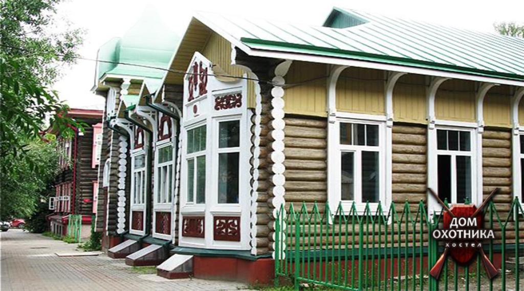 una casa de madera con un cartel delante en Hostel Hunter House, en Tomsk