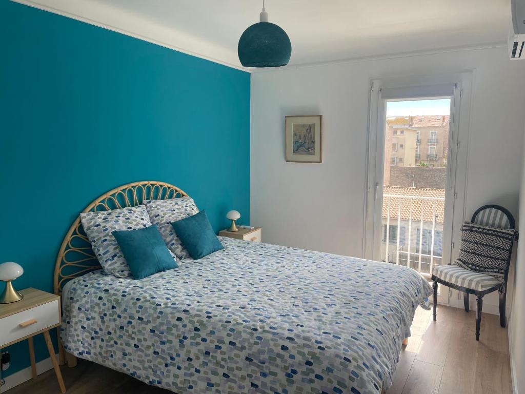 une chambre bleue avec un lit et une fenêtre dans l'établissement Le Mercier - T3 climatisé avec balcon, à Sète