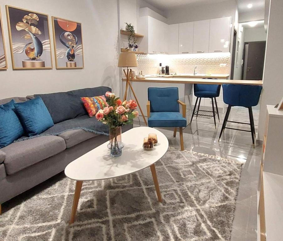 een woonkamer met een bank en een tafel met een vaas met bloemen bij Delta - Central Elegant Apartment in Kateríni