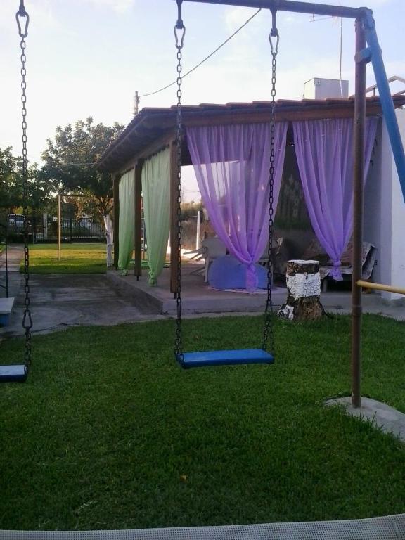 a swing set in a yard with purple curtains at ANASTASIA HOUSE in Sozopoli