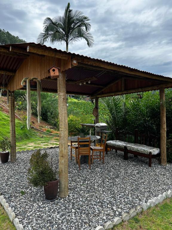 a gazebo with a table and a bench and a table and chairs at Chalé de Madeira em Vargem Alta in Vargem Alta